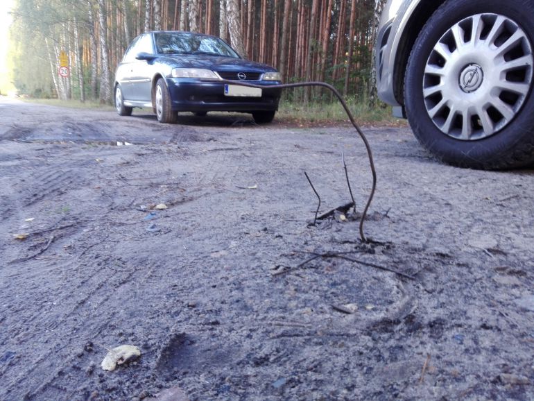 Z gruntowej drogi wystają druty
